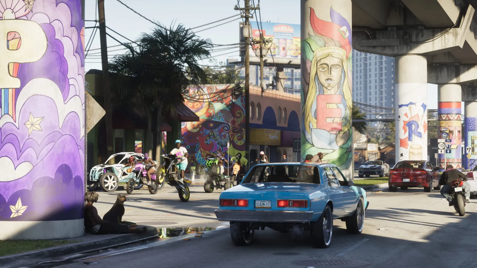 Vida callejera en Vice City, un clásico muscle car pasando junto a murales pintados a mano.